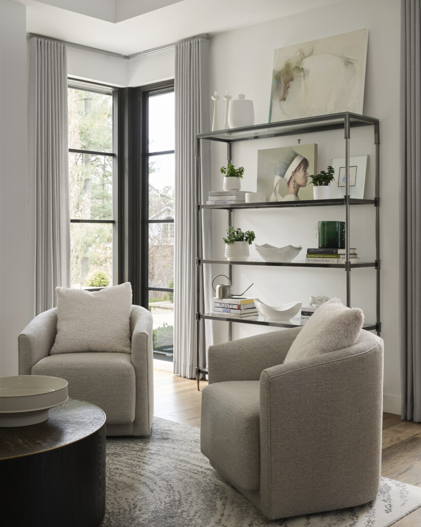 Sitting area with two white fabric chairs and a bookshelf.