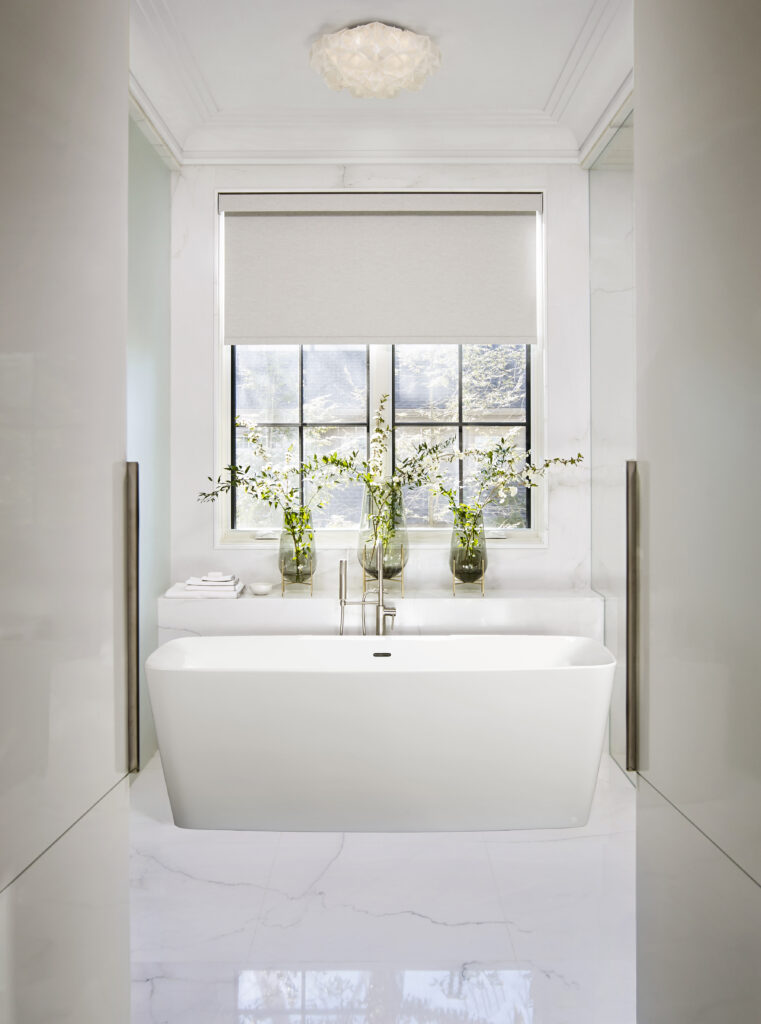 Bathtub in front of window with flowers on the ledge
