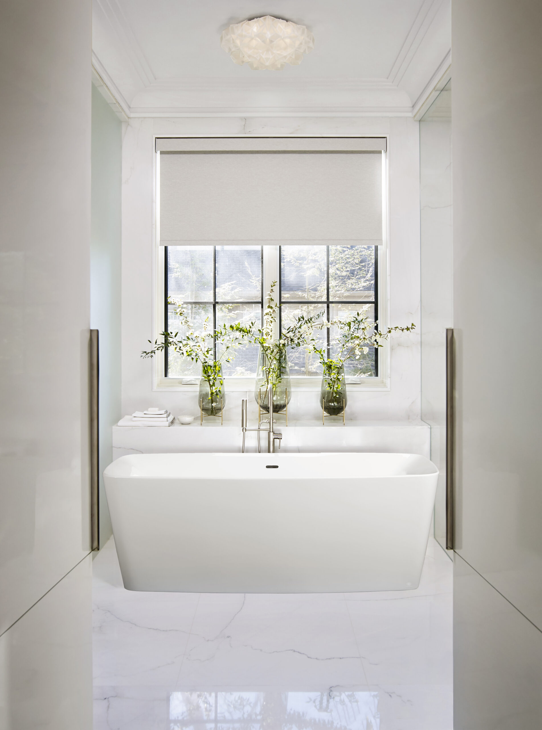 Bathtub in front of window with flowers on the ledge