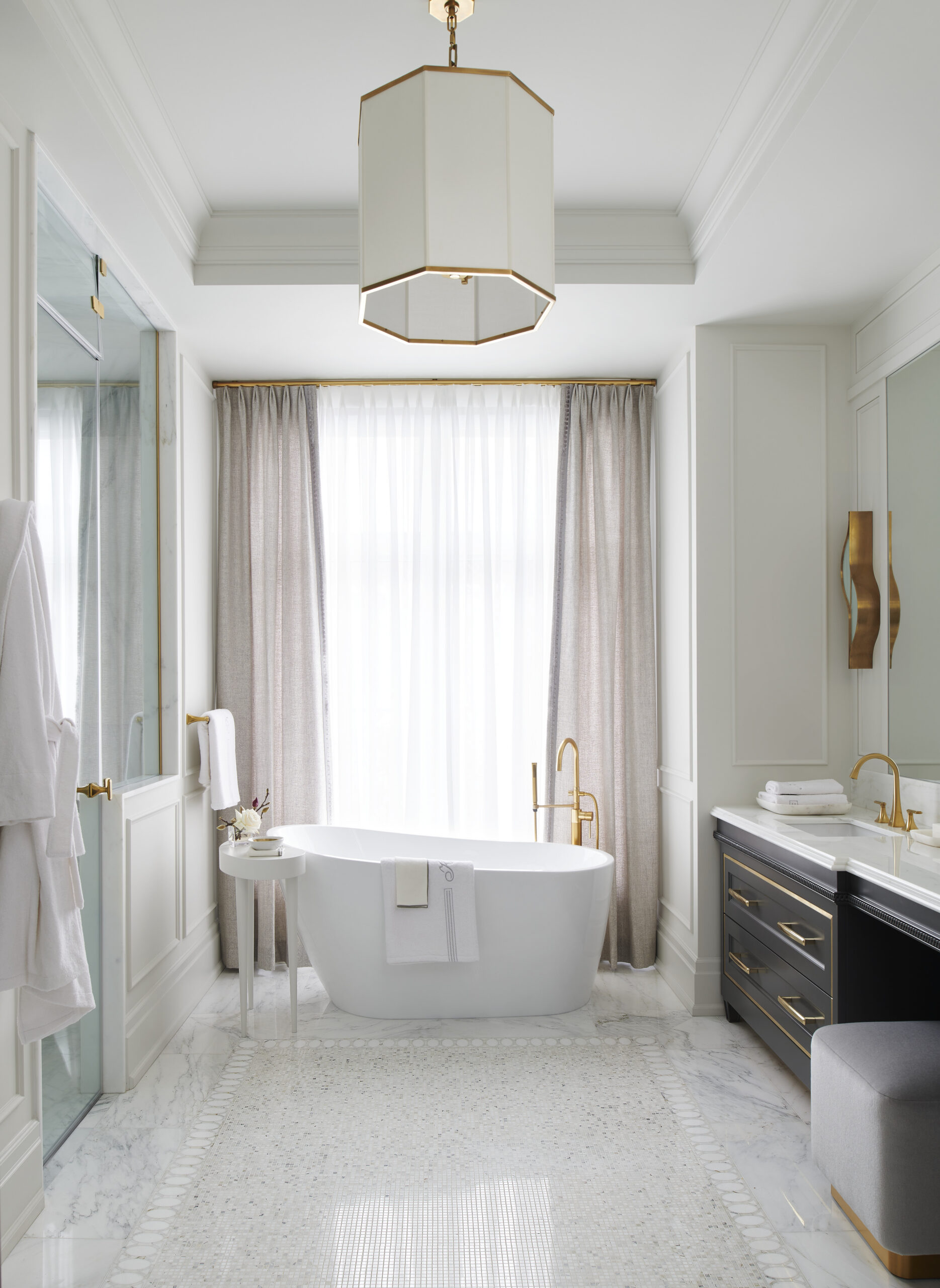 Signature suite - modern luxury bathroom with a big white bath tub, black counters and a white chandelier with gold accents