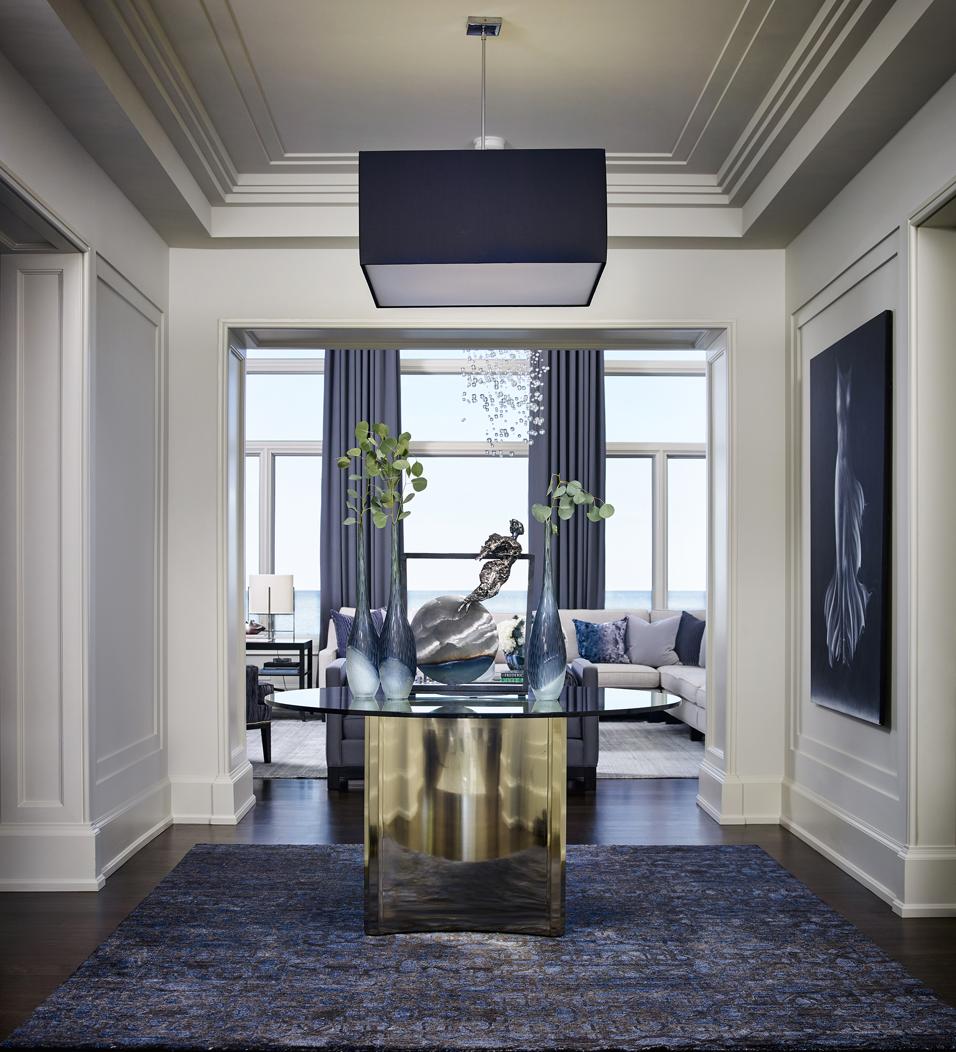 Glass table with metal statue in hallway leading to living room