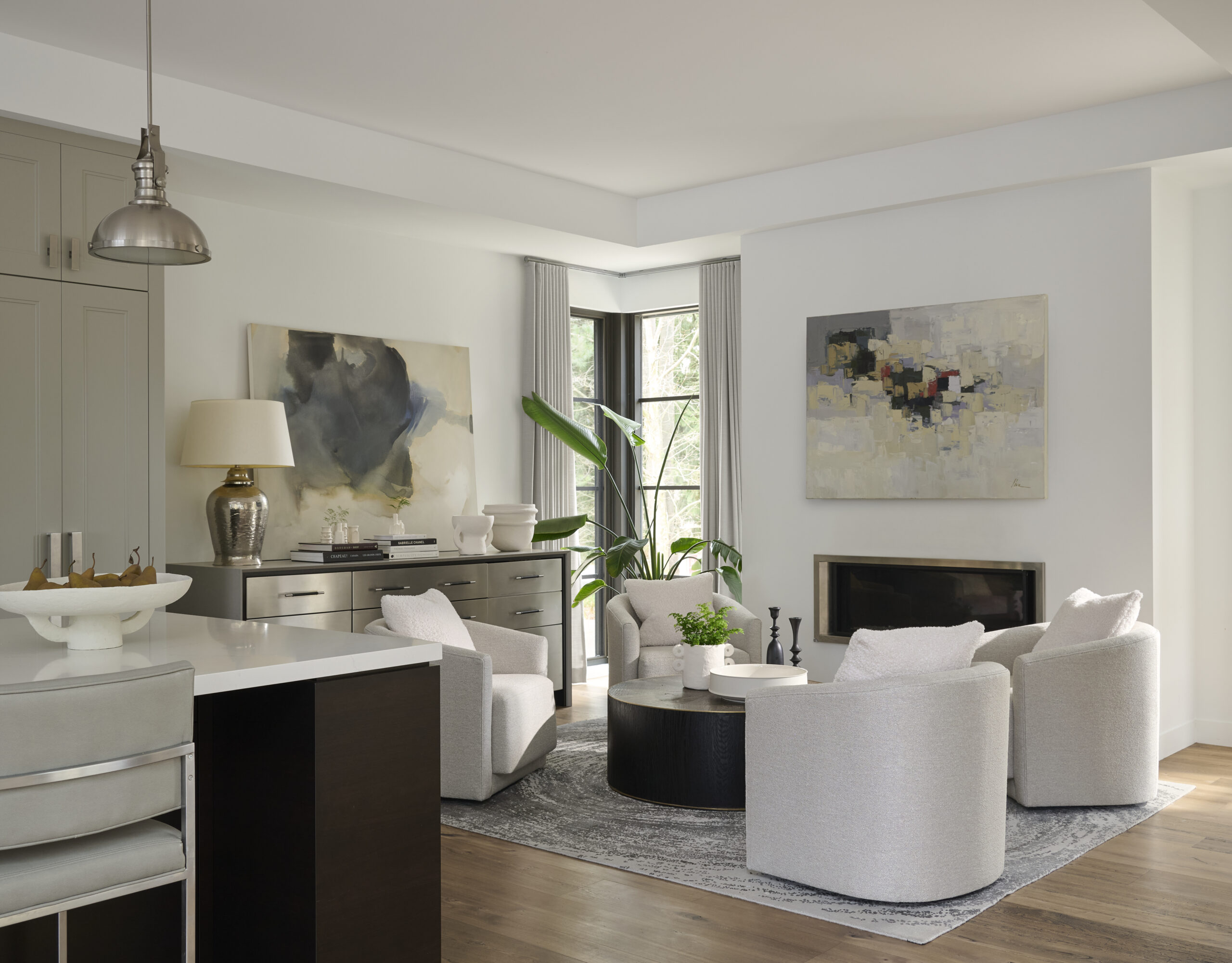 Wide view of the sitting area next to the kitchen with four white chairs and a fireplace