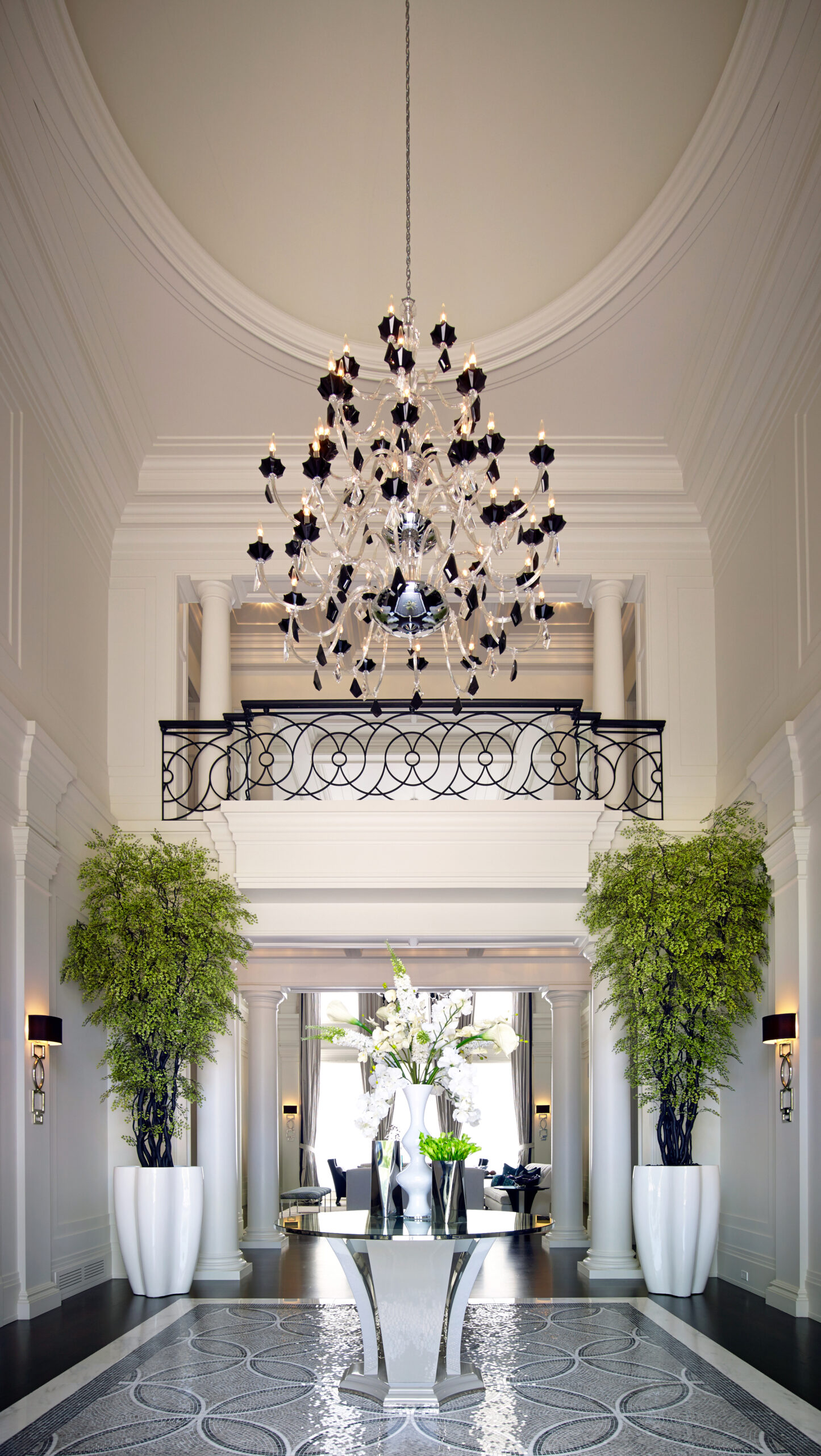 Luxury home entryway with a black chandelier and two huge indoor plants
