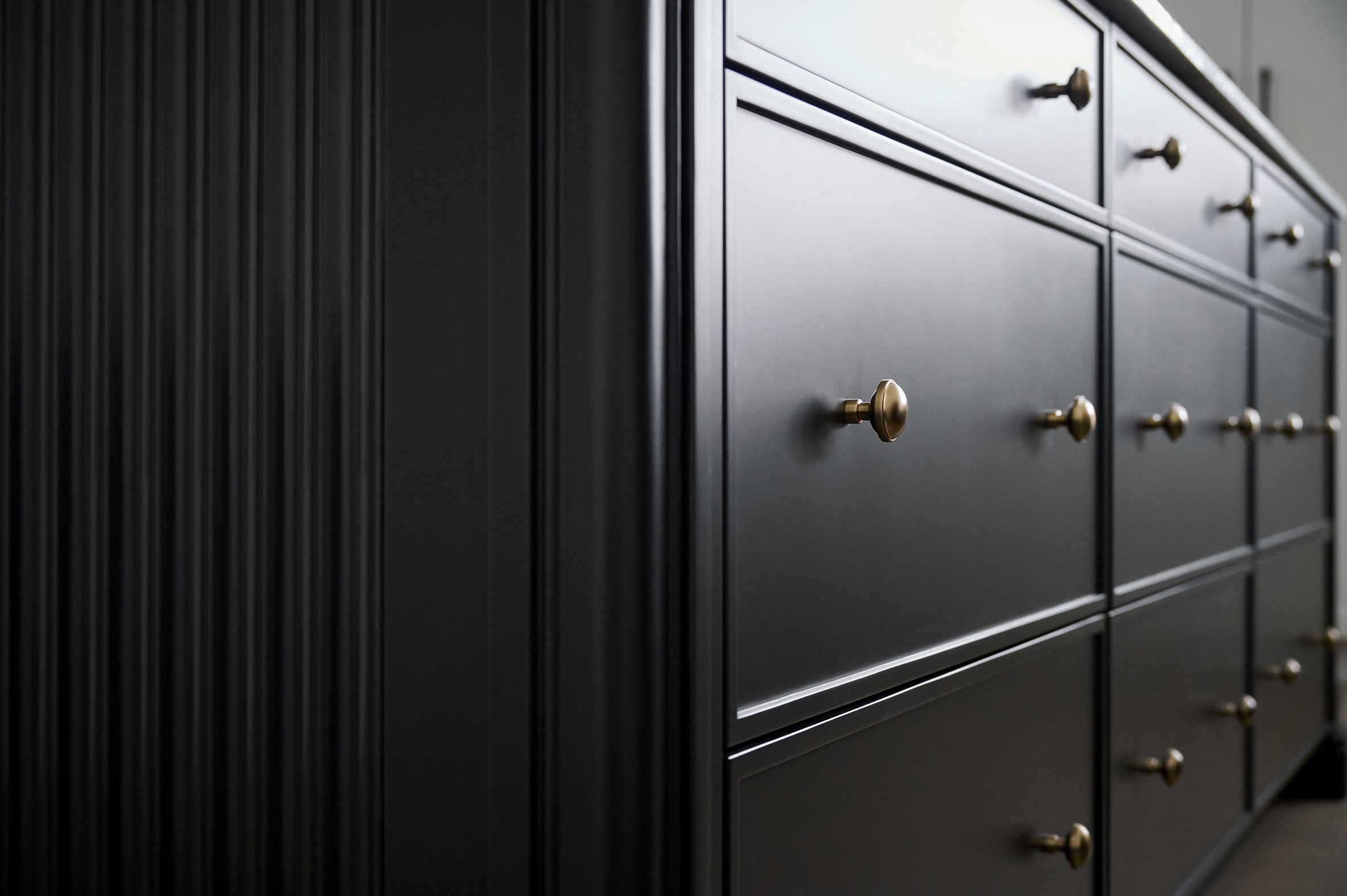 Black kitchen cabinets and drawers with gold knobs