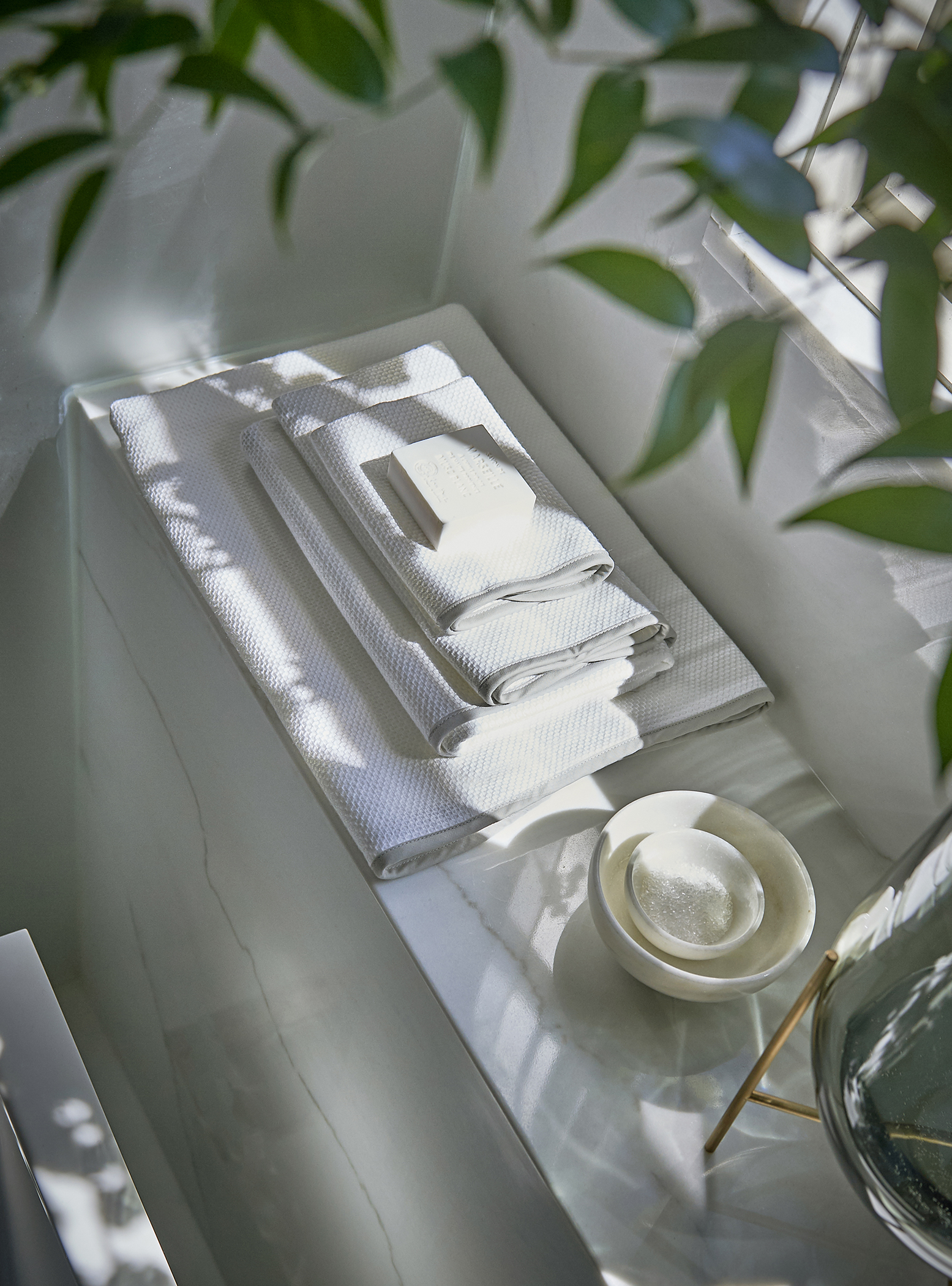 Towels and soap on white marble ledge in bathroom