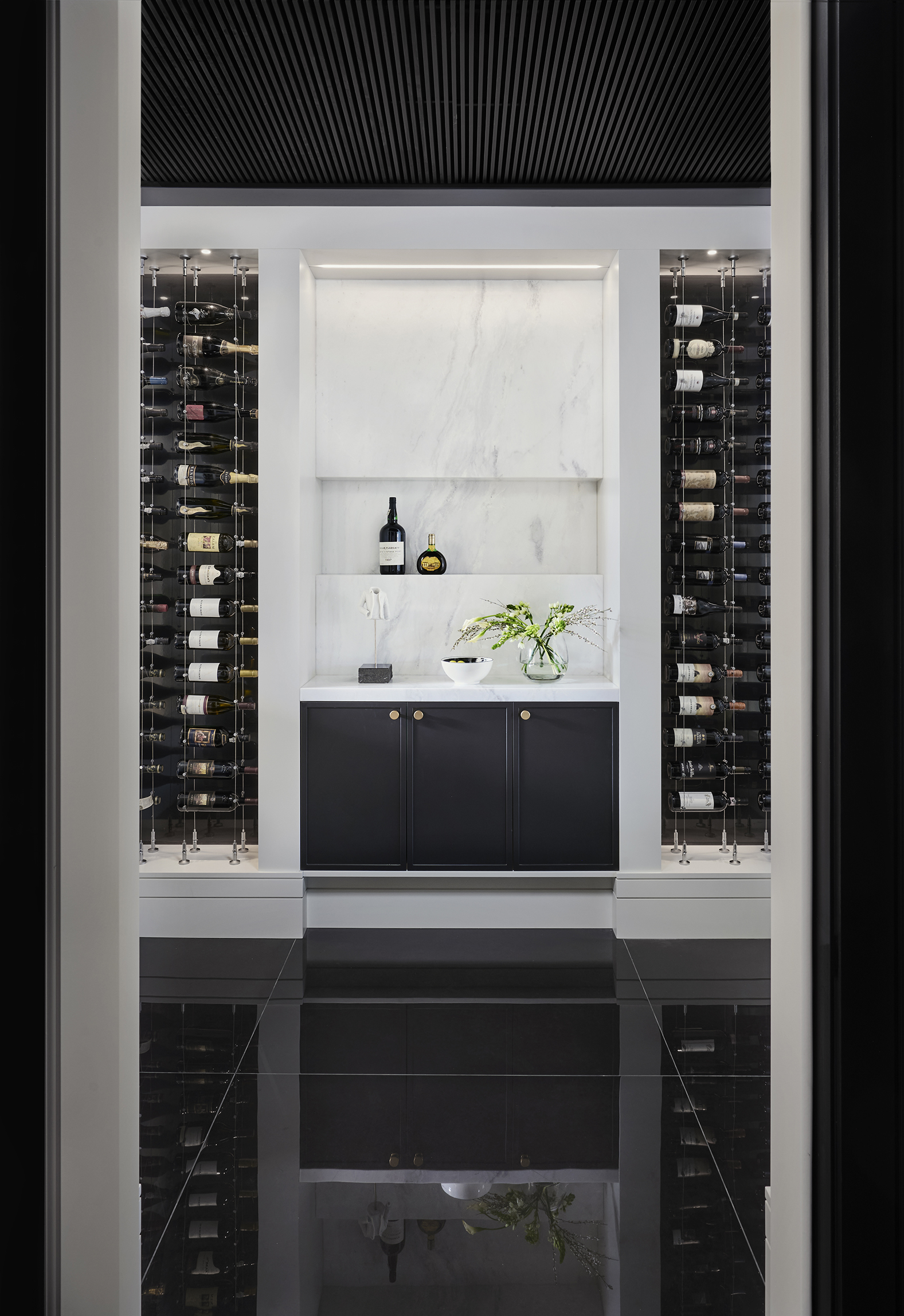 Wine room with black tiles, clack cabinets and white walls