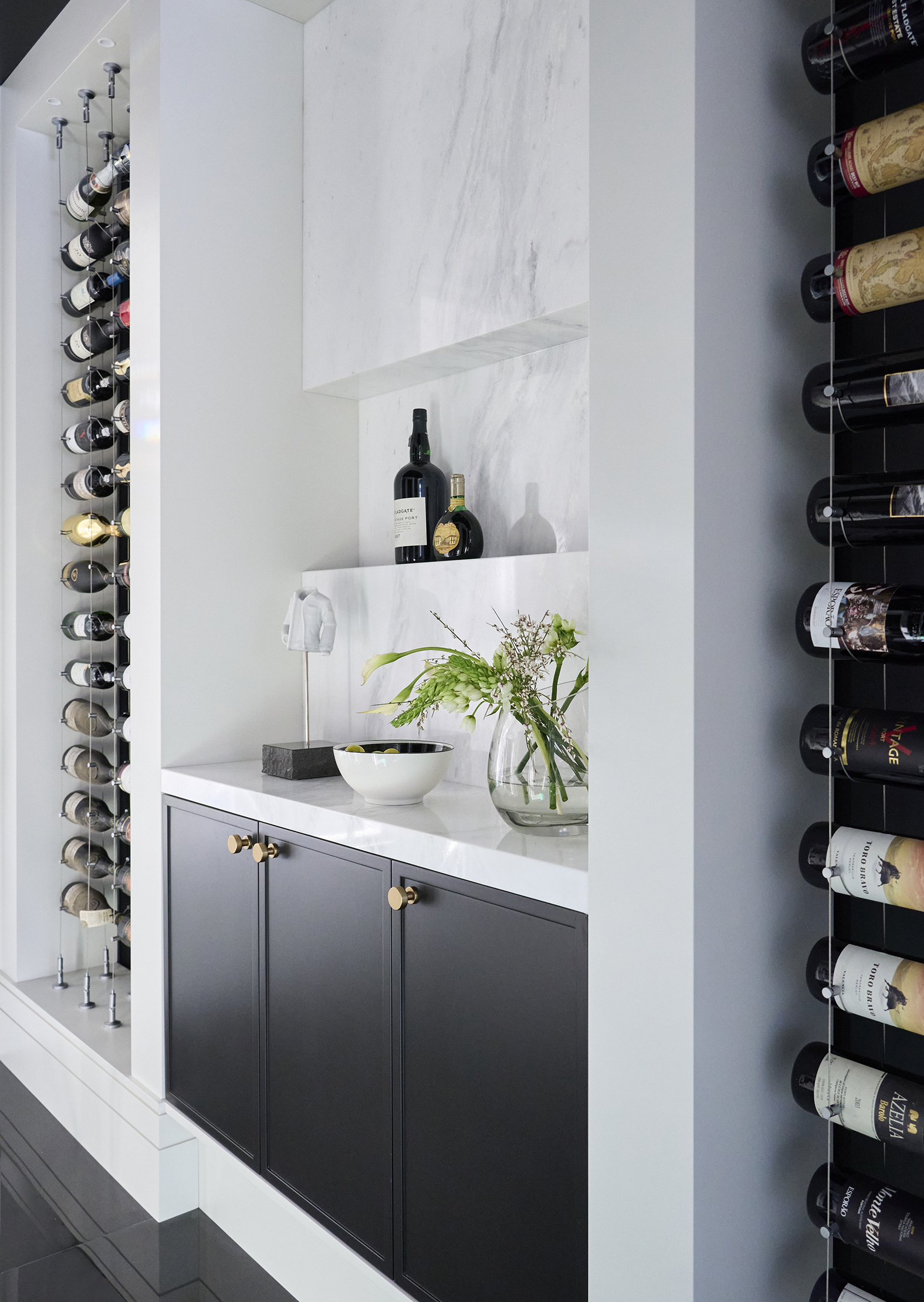 Wine room with black tiles, black cabinets and white walls