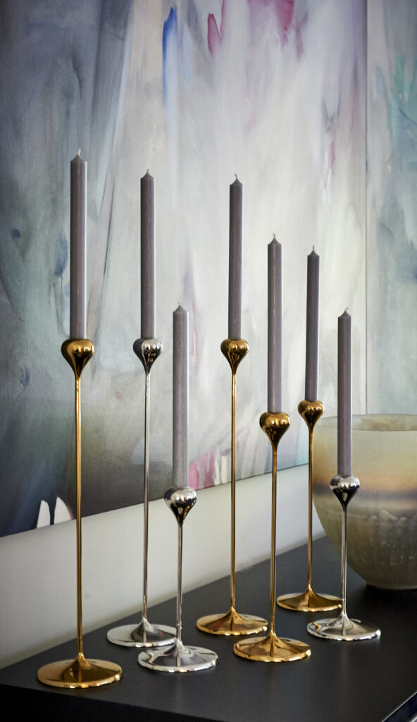 Bronze and silver candle sticks in front of colourful painting