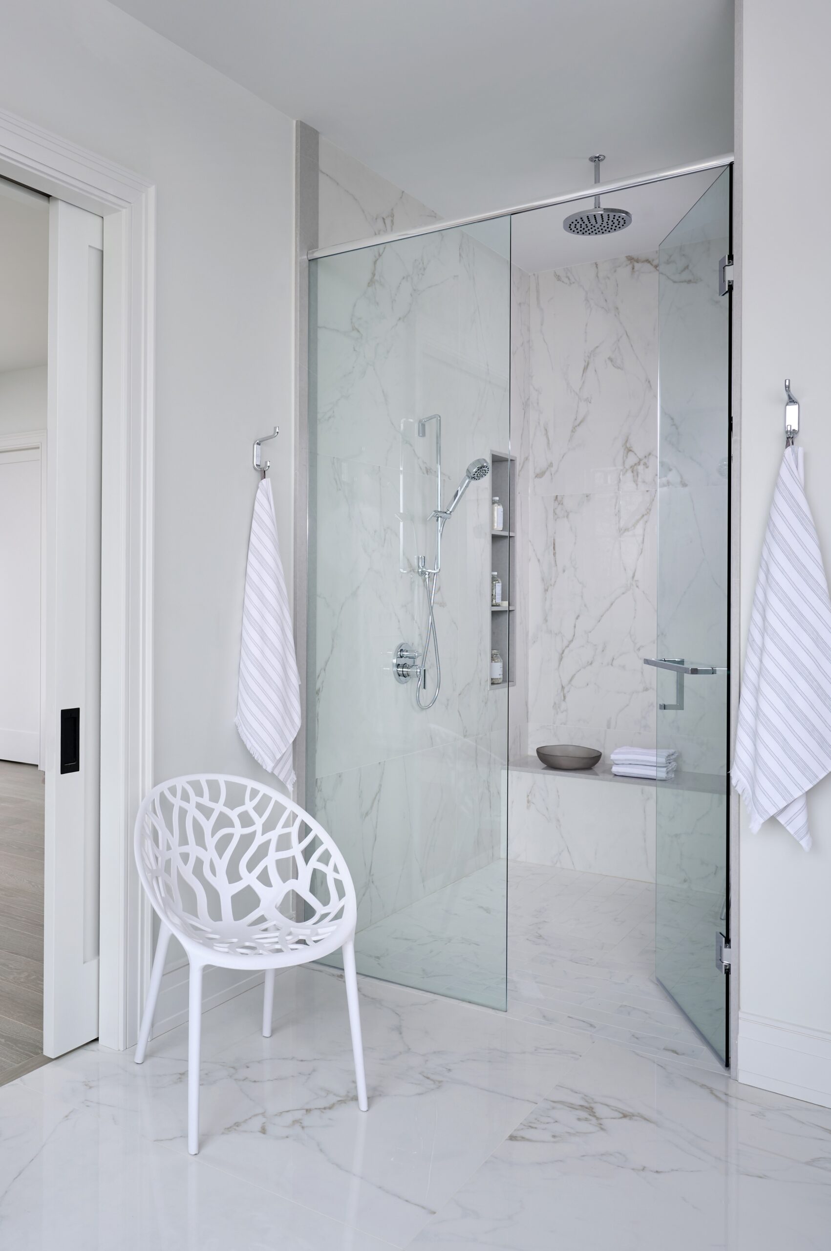 White marble shower with chair in front